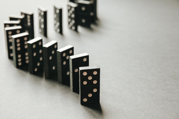 Chaîne de dominos noirs sur un fond de tableau blanc Concept d'effet Domino