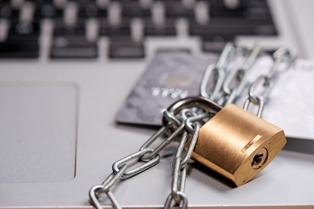 Chaîne lourde avec un cadenas autour d'un ordinateur portable et d'une carte de crédit sur la table.