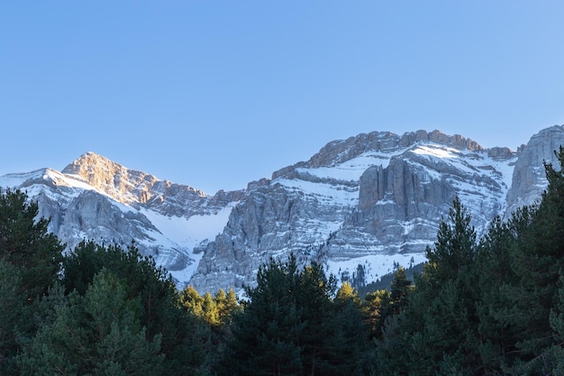 Une chaîne de montagnes avec un ciel bleu et le soleil qui brille sur la neige.