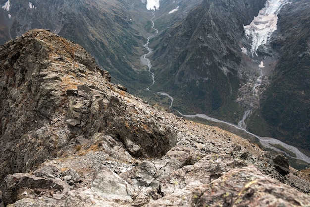 Chaîne de montagnes enneigées dans les nuages. Vallée avec un ruisseau de montagne. Caucase, Russie