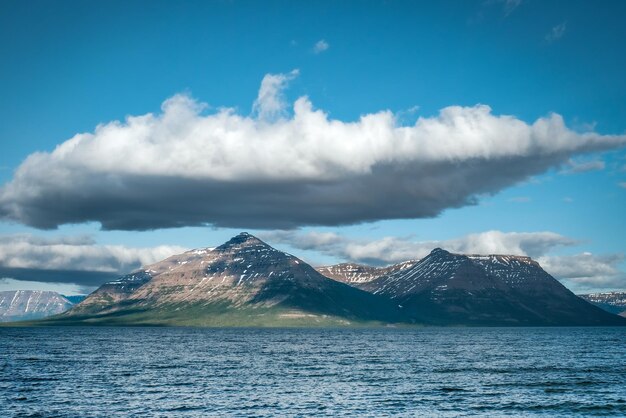 Photo une chaîne de montagnes est vue au loin, avec un ciel bleu et des nuages au-dessus.