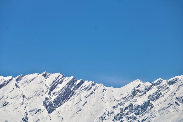 Photo une chaîne de montagnes avec de la neige au sommet et un ciel bleu en arrière-plan.