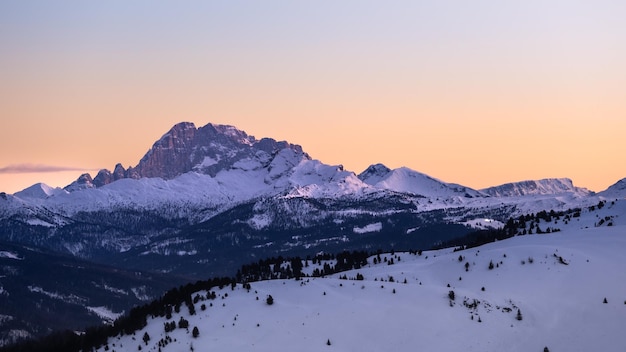 Une chaîne de montagnes avec de la neige au sommet et un ciel rose en arrière-plan