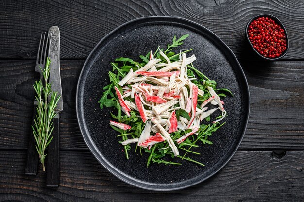 Chair de crabe sur une assiette avec roquette. Fond noir. Vue de dessus.