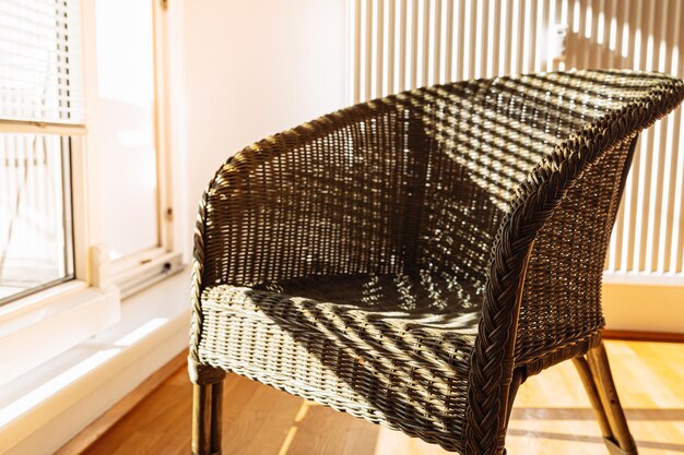 Chaise en bambou en osier près d'un balcon ouvert dans les rayons du soleil éclatant, sur fond
