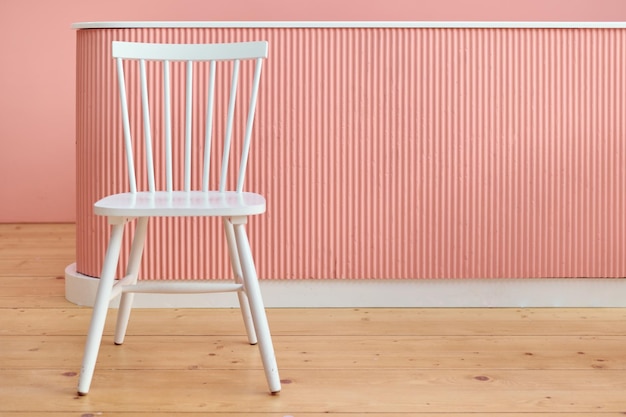 Photo chaise blanche dans l'espace salon fond rose et concept minimal de plancher en bois