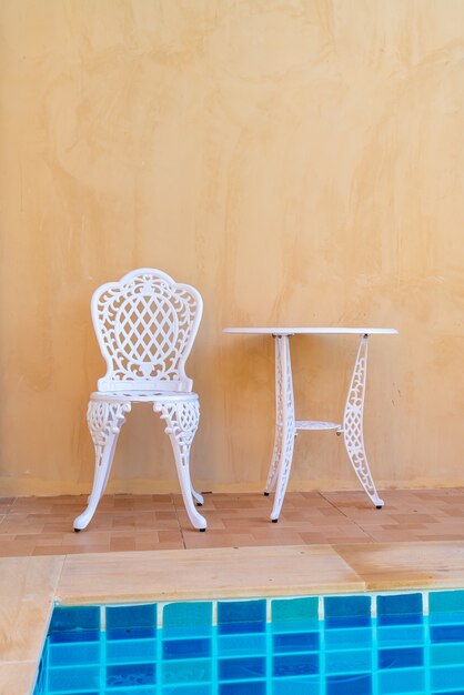 Chaise blanche vide et table sur le côté de la piscine