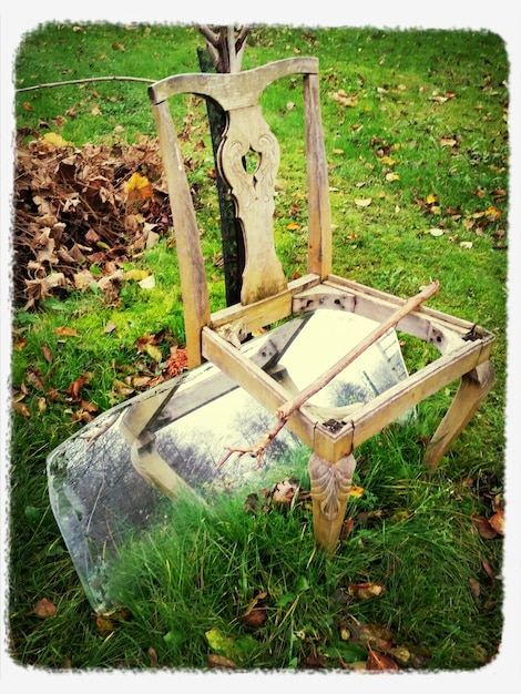 Photo une chaise en bois abandonnée sur un champ herbeux.