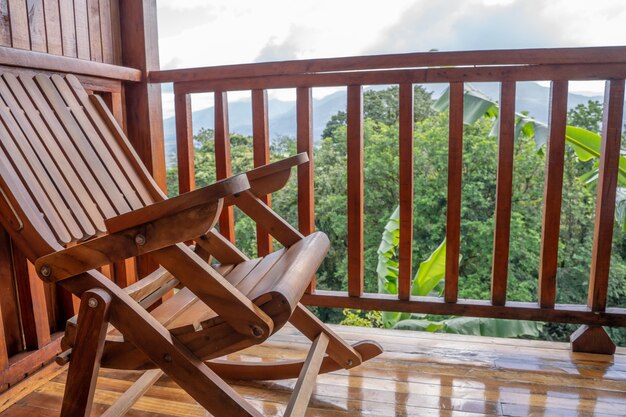 Chaise en bois dans une terrasse en bois d'un hôtel avec vue sur la jungle et un volcan en arrière-plan