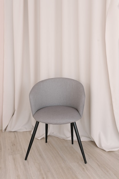 Chaise élégante grise dans la perspective des rideaux du salon