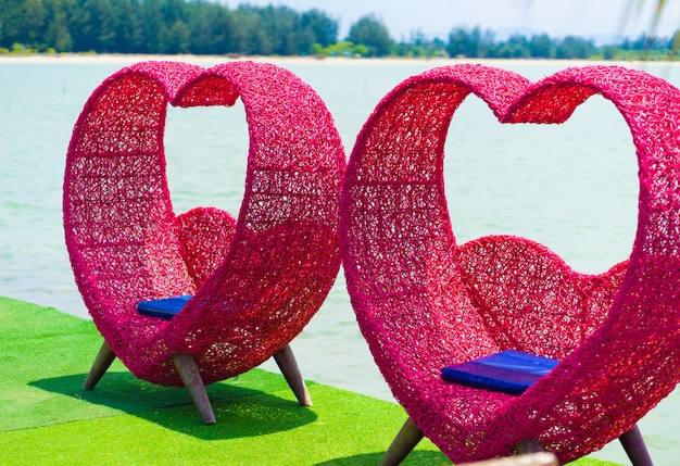 Chaise en forme de coeur rose sur la plage.