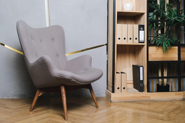 Chaise grise recouverte de textiles avec pieds en bois dans un intérieur de bureau moderne