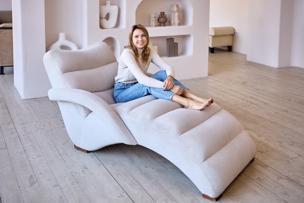 Chaise longue avec femme heureuse mince qui s'assied dessus