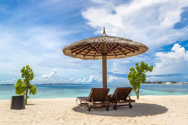 Chaise longue et parasol sur la plage tropicale aux Maldives