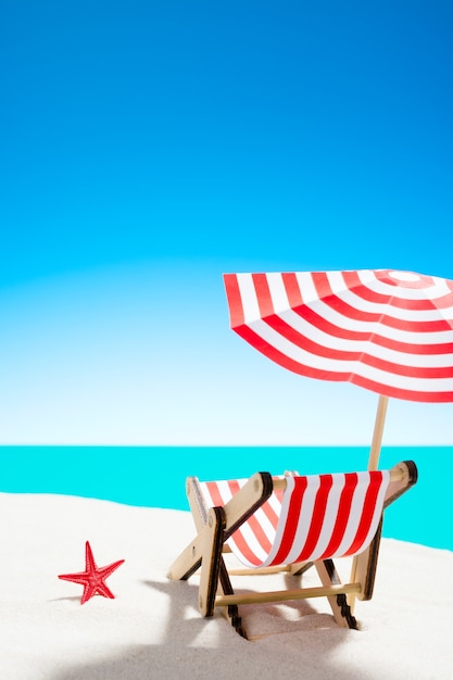 Une chaise longue sous un parasol sur la plage de sable au bord de la mer