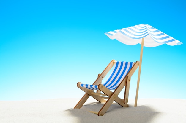 Une chaise longue sous un parasol sur la plage de sable, ciel avec espace copie