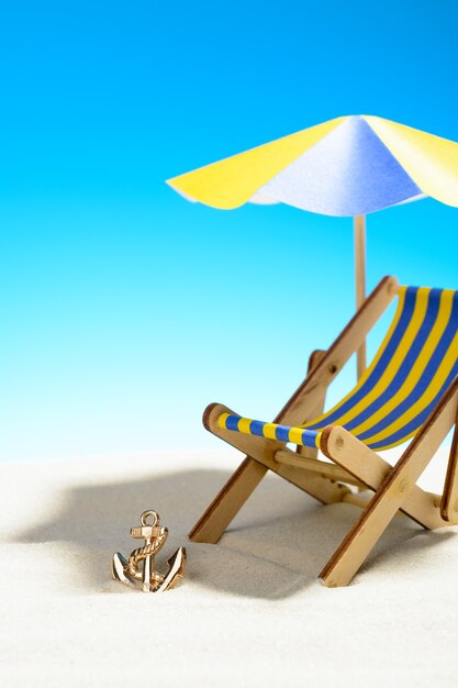 Une chaise longue sous un parasol sur la plage de sable, ciel avec espace copie