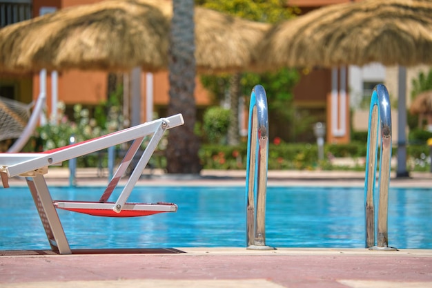 Chaise longue vide au bord de la piscine dans la station balnéaire. Concept de vacances et d'escapade.