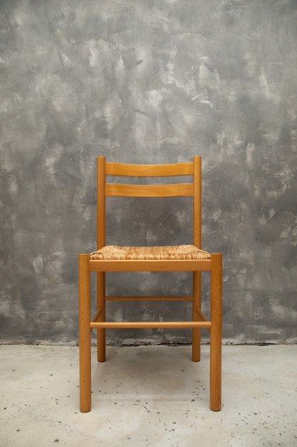 chaise en osier sur mur de béton gris à l'intérieur, espace vide, espace de copie pour le texte. Élément intérieur, mobilier