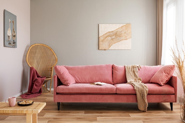 Chaise paon en osier avec couverture rouge derrière un canapé en velours rose