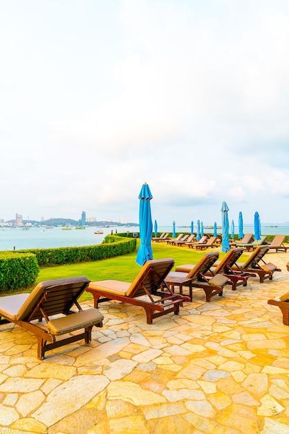 Chaise piscine ou lit piscine et parasol autour de la piscine avec fond de plage de la mer à Pattaya en Thaïlande