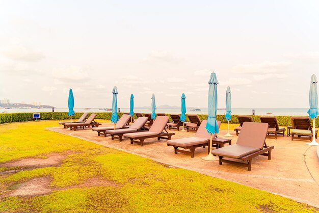 chaise piscine ou lit piscine et parasol autour de la piscine avec fond de plage de mer à Pattaya en Thaïlande