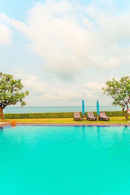 chaise de piscine et parasol autour de la piscine avec mer océan