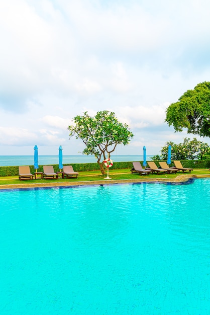 chaise de piscine et parasol autour de la piscine avec mer océan