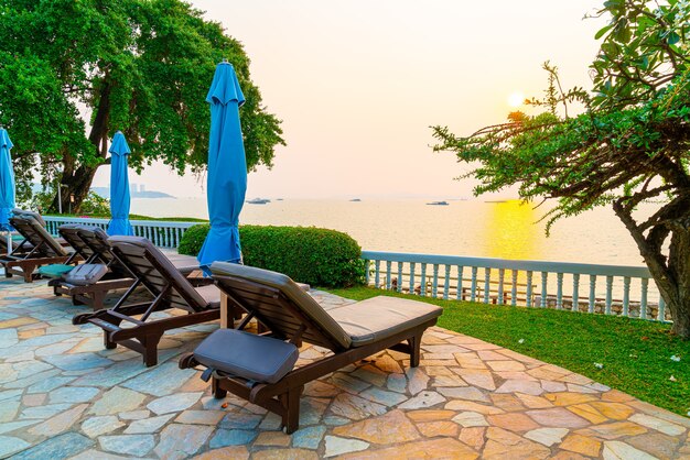 chaise de plage ou lit de piscine avec parasol autour de la piscine au coucher du soleil