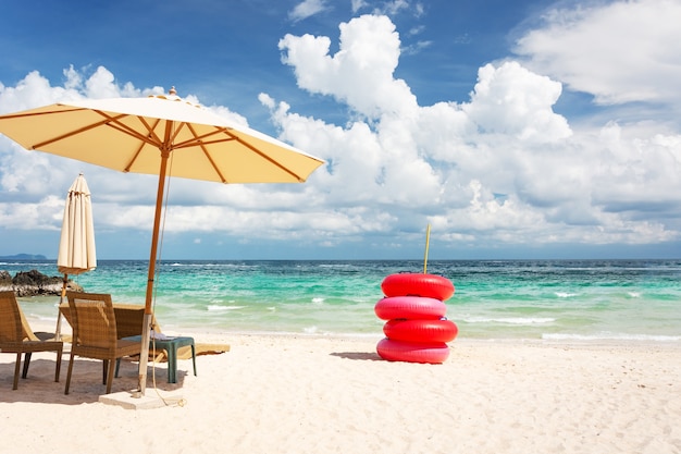 Photo chaise de plage, parapluie et bouée de sauvetage rouge sur la plage et la mer verte, sur un bon d