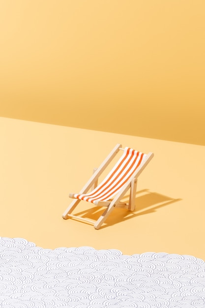 Une chaise de plage à rayures rouges pour les bains de soleil et les vagues de papier Concept d'été et de vacances