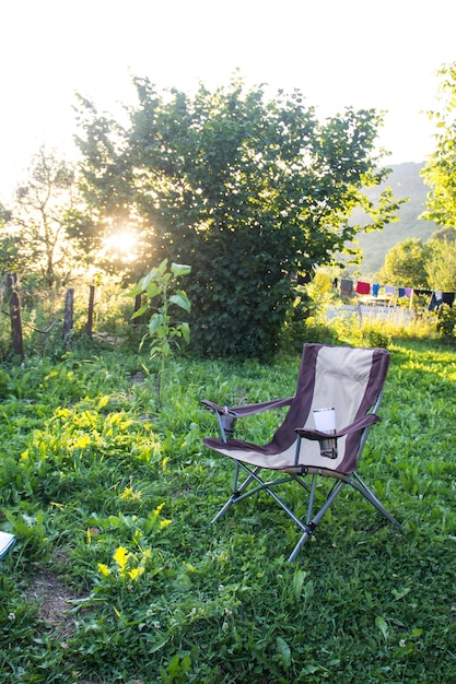 Une chaise pliante vide pour le camping en plein air sur fond de nature au coucher du soleil