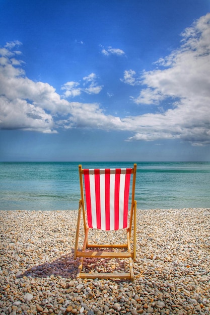 Une chaise de pont sur la plage contre le ciel