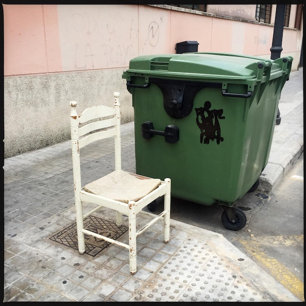 Photo une chaise près d'une poubelle sur le trottoir.