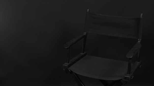 Chaise de réalisateur isolée. Elle est utilisée dans la production vidéo ou l'industrie du cinéma et du cinéma. Il est mis sur fond NOIR. .