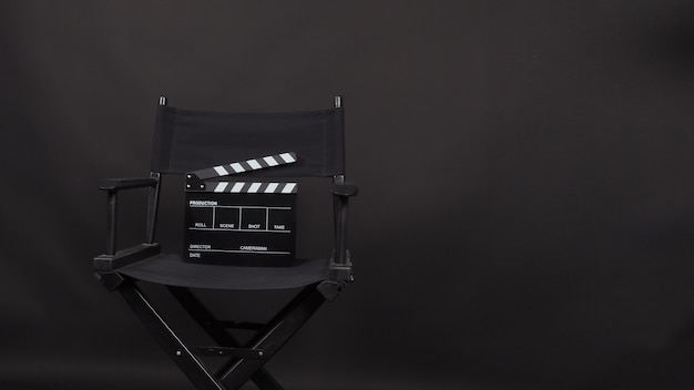 Chaise de réalisateur noire, Clapperboard, utilisation de l'ardoise de film dans la production vidéo sur fond noir.