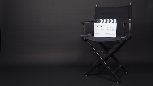 Chaise de réalisateur et panneau de clapet noir ou utilisation d'ardoise de film dans la production vidéo et le cinéma, le cinéma, l'industrie du cinéma sur fond noir. Il a écrit en nombre.