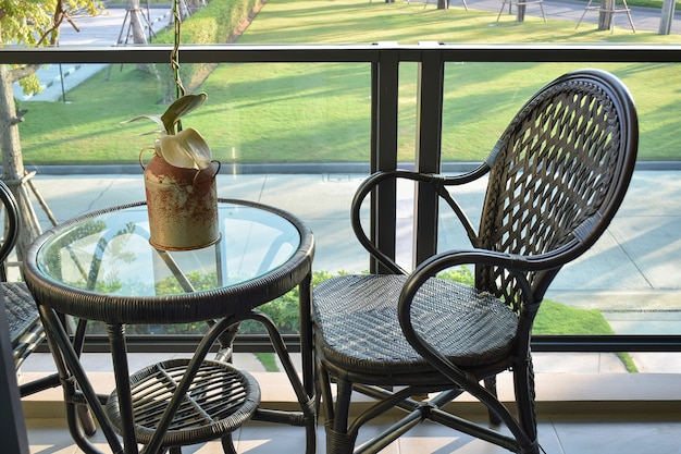 Chaise en rotin brun sur un balcon moderne donnant sur un jardin