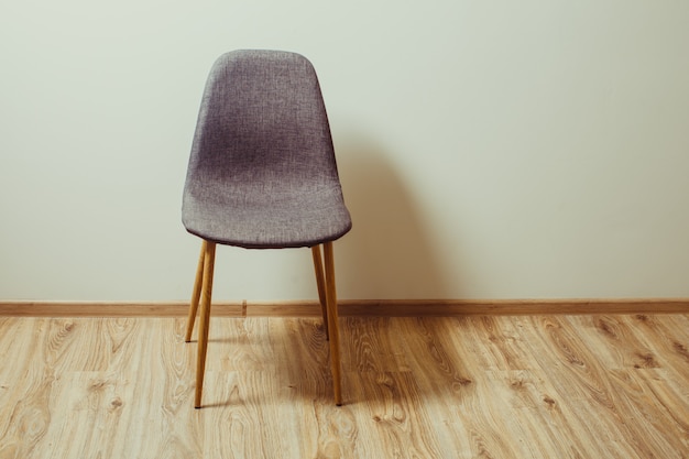 La chaise se tient près du mur dans la pièce vide