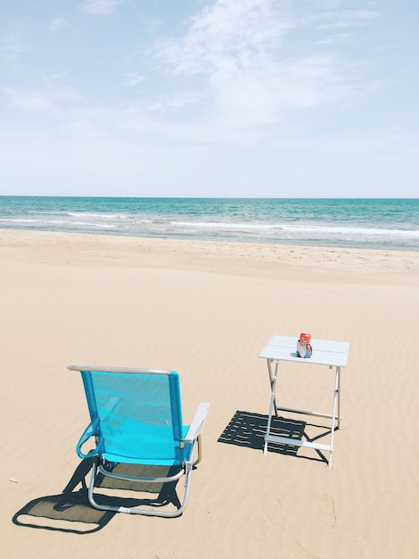 Une chaise et une table sur la plage contre le ciel