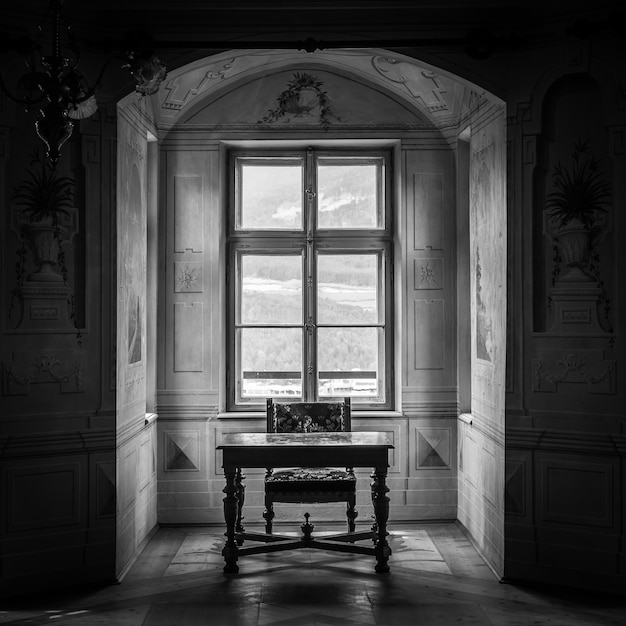 Une chaise et une table solitaires dans une vaste salle du château de Savoia, bâtiment de style architectural typiquement Walsen.