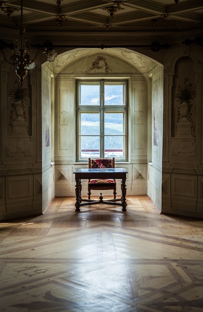 Une chaise et une table solitaires dans une vaste salle du château de Savoia, bâtiment de style architectural typiquement Walsen.