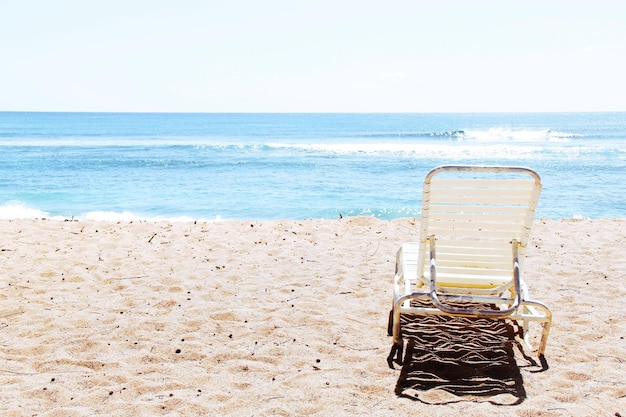 Une chaise vide sur la plage contre un ciel clair