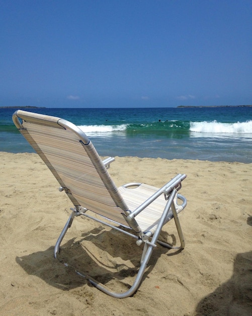 Une chaise vide sur la plage contre le ciel