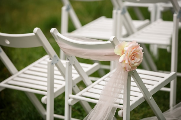 Chaises blanches avec rose pour mariage