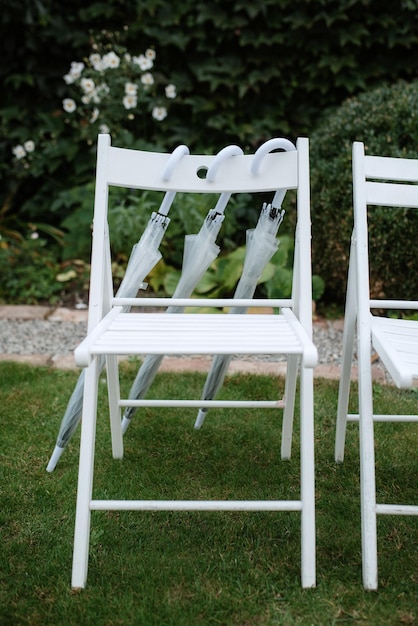 Chaises en bois blanches pour la cérémonie de mariage sur l'herbe verte