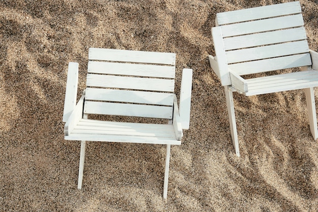 Chaises en bois sur une plage de sable fin.