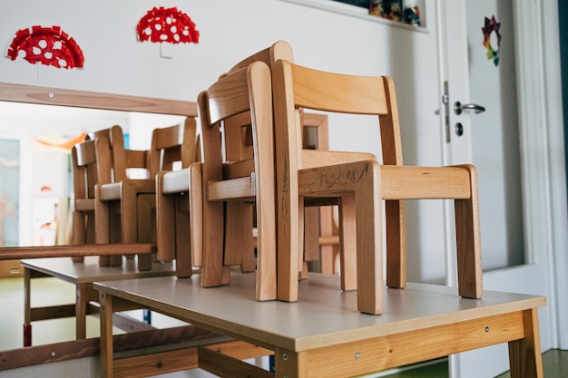 Des chaises en bois sur une table dans un jardin d'enfants vide