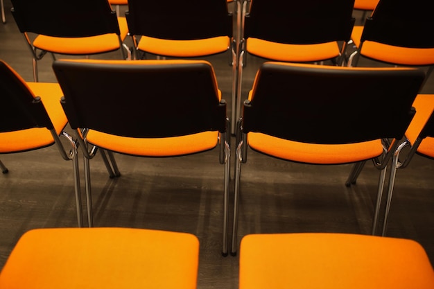 Chaises de conférence en plastique noir et orange Chaises noires et orange dans la salle de conférence