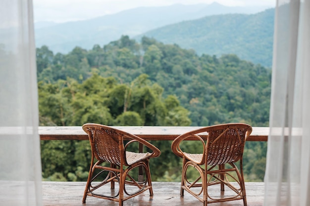 Chaises de couple sur le balcon de la maison de campagne ou chez l'habitant avec vue sur la montagne en arrière-plan le matin